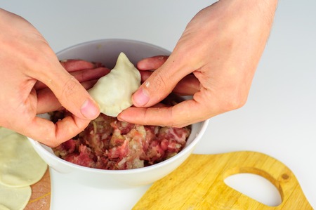 Man hands making homemade dumplings with meatの写真素材