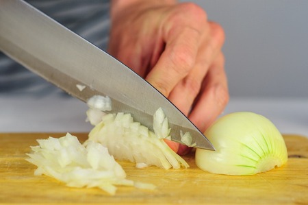 Man hands cutting onion on wooden boardの写真素材