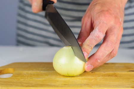 Man hands cutting onion on wooden boardの写真素材
