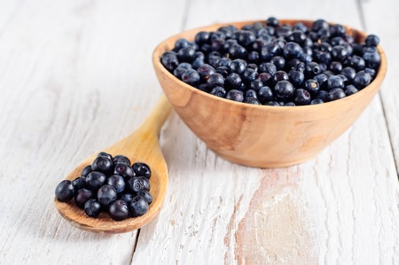 Wooden bowl with forest blueberry on white wooden backgroundの写真素材