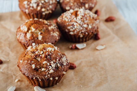 Homemade banana peanut muffins on baking paper and white wooden backgroundの写真素材