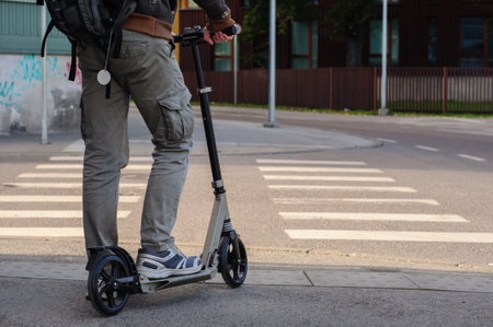 Young man in casual wear on kick scooter on city street