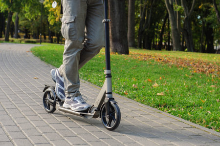 Young man in casual wear on kick scooter on city street