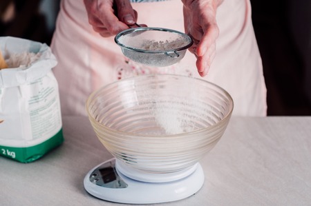 Man chef sifting flour for pizza doughの写真素材