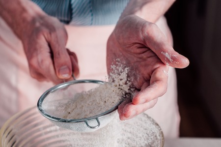 Man chef sifting flour for pizza doughの写真素材