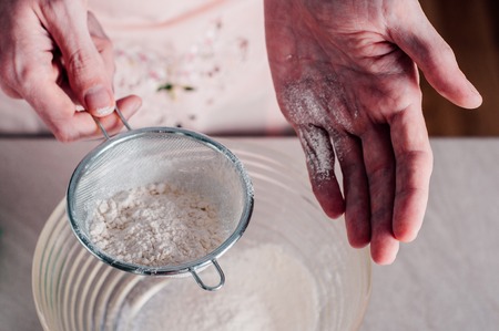 Man chef sifting flour for pizza doughの写真素材
