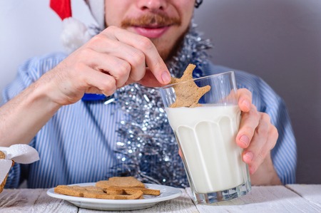 Young man eating christman gingerbread cookies with glass of milkの写真素材