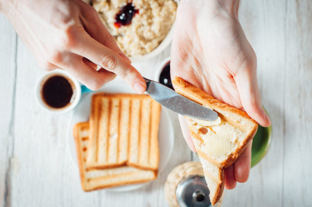 Man hands eating coffee and toast with butter and jam for breakfast