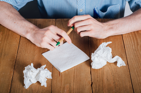 Young man with beard writing on napkinの写真素材