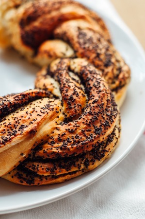 Estonian pastry kringel with poppy seeds at sunshine morning on wooden backgroundの写真素材