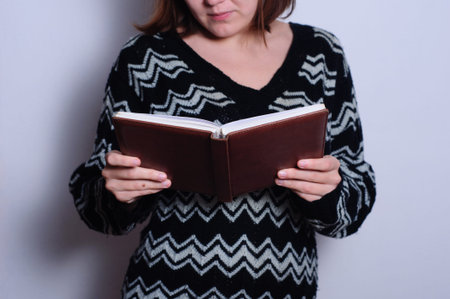 Young woman student studying reading paper  notebook in sweater