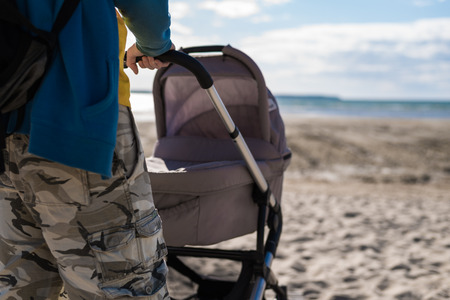 Young dad with baby stroller on beachの写真素材