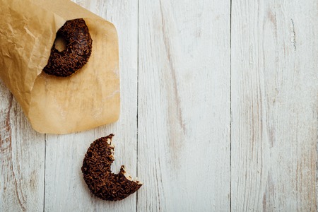 Chocolate doughnut in paper on wooden tableの写真素材