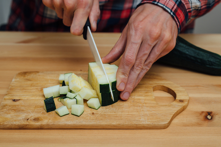Man hands slicing fresh zucchini on chopping boardの写真素材