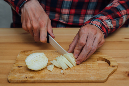 Man hands slicing fresh onion on chopping boardの写真素材
