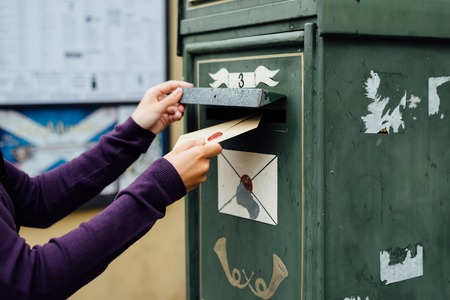 Mailing letter with wax seal to old postbox on streetの写真素材
