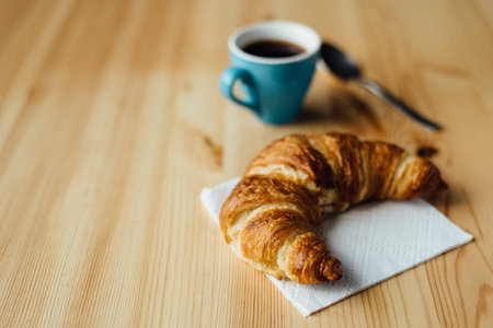 Breakfast with coffee and croissant on wooden table
