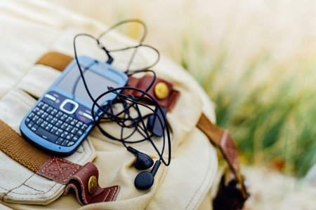 Blue old fashioned smart phone with  qwerty keypad and headset on backpackの写真素材