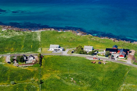 Top view to Norway village on coast. Traditional norwegian cabins near sea on green fieldの写真素材