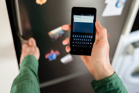 Close-up of person hands holding smartphone showing web browser search tool with virtual keyboard on...