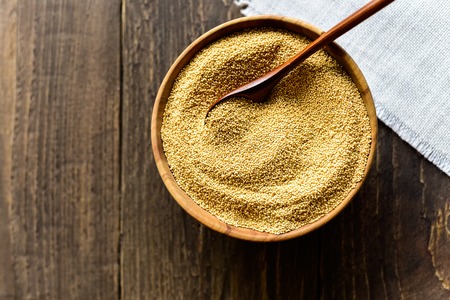 Wooden bowl and spoon with raw amaranth seeds on wooden backgroundの写真素材