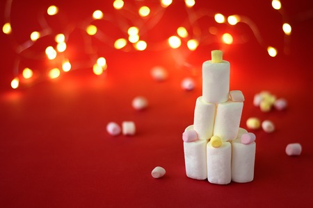 Marshmallow christmas tree on red background with festoon and sparkler lights in bokehの写真素材
