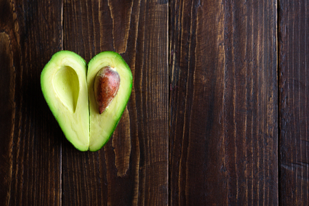 Heart shaped avocado half on wooden backgroundの写真素材