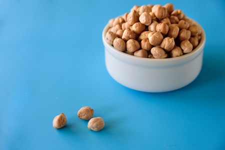 Ceramic bowl with raw chickpeas on light blue backgroundの写真素材