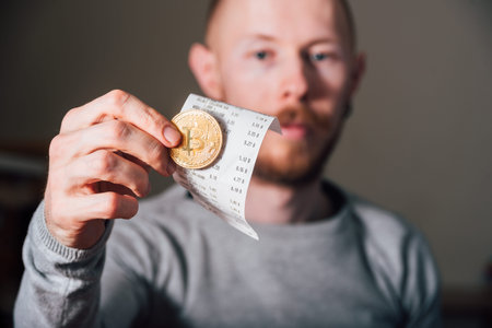 Young Man with beard paying his bill with bitcoin gold coin