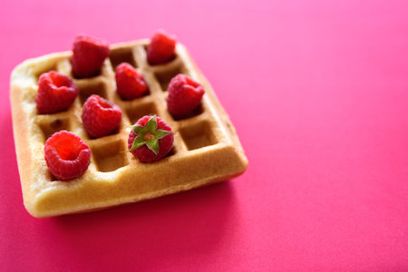 Belgian waffles with raspberries on red background