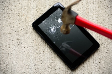 Hammering screen of tablet by old rusty hammer on concrete backgroundの写真素材