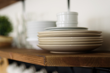 Close-up of plates and cups on open wooden shelf in modern kitchenの写真素材