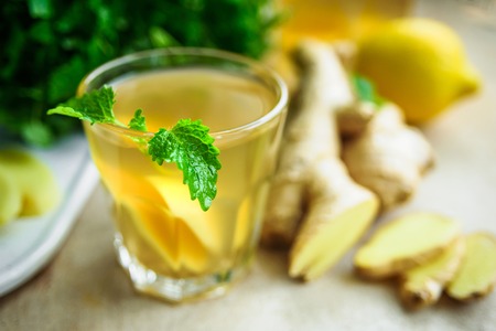 Glass with ginger detox water and ingredients near it. Wooden background.の写真素材