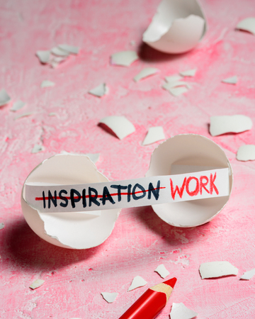 Work hard and inspiration concept. Cracked egg on pink background with text INSPIRATION and WORK. Like fortune cookiesの写真素材
