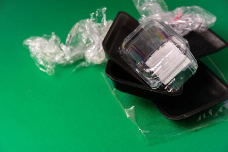 Plastic used disposable food package on green background. Plastic waste, recycle conceptの写真素材