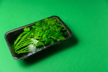 Fresh petersell in plastic package. Zero waste, recycle concept. Plastic pollution. Green background