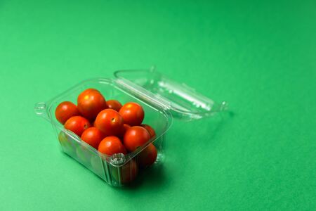 Fresh cherry tomatoes in plastic package. Zero waste, recycle concept. Plastic pollution. Green backgroundの写真素材