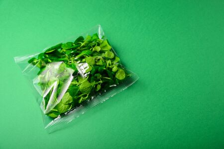 Fresh baby greens in plastic package. Zero waste, recycle concept. Plastic pollution. Green backgroundの写真素材