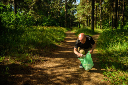 Man collecting garbage in forest. At jogging or running. Plogging conceptの写真素材