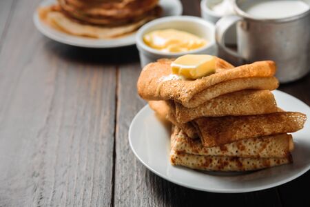 Russian pancakes blini with piece of butter on dark wooden backgroundの写真素材