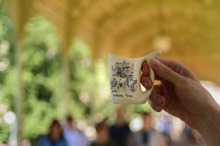 Man holding special mug for water from hot mineral spring in Karlovy Varyの写真素材