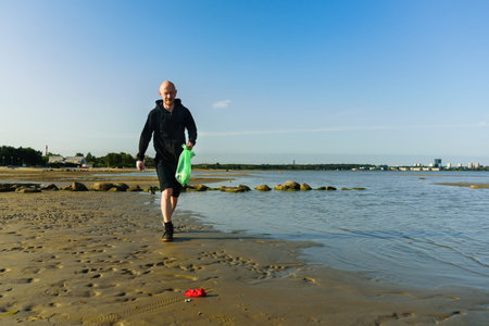 Man picking garbage on beach. At jogging or running. Plogging concept