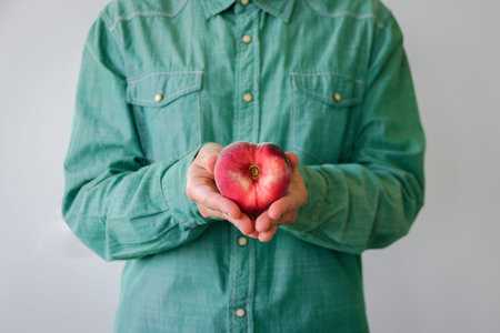 Man in green shirt with heart shaped peach in his hands