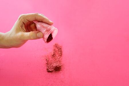 Menstrual cup full of red glitter in woman hand on pink background. Periods, eco alternative, reusable replacementの写真素材