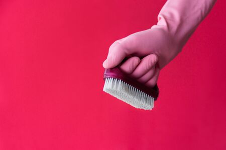 Hand in pink latex protective glove with dust brush on pink background. Cleaning and housework work conceptの写真素材