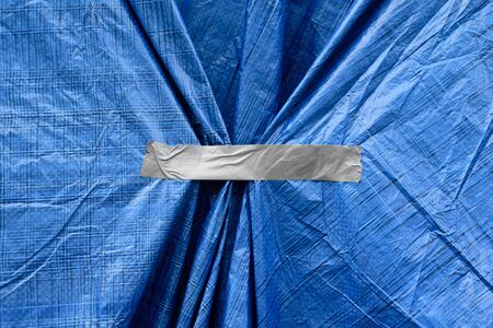 Silver tape on blue plastic sackcloth. Folds, wrinkles, weight loss conceptの写真素材