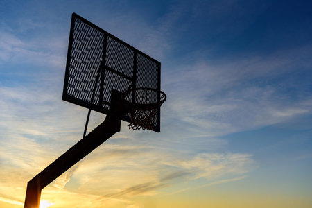 Street basketball hoop on sunset sky. Goal and win concept
