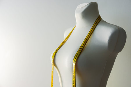 Tailor mannequin with yellow measuring tape on grey backgroundの写真素材