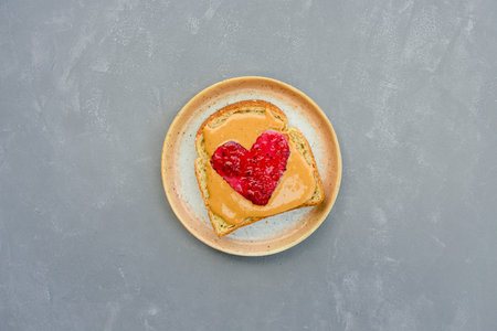 Peanut butter jelly heart sandwich on modern plate and grey concrete background. Valentines day...