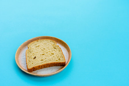 Piece of bread on modern plate and light blue backgroundの写真素材